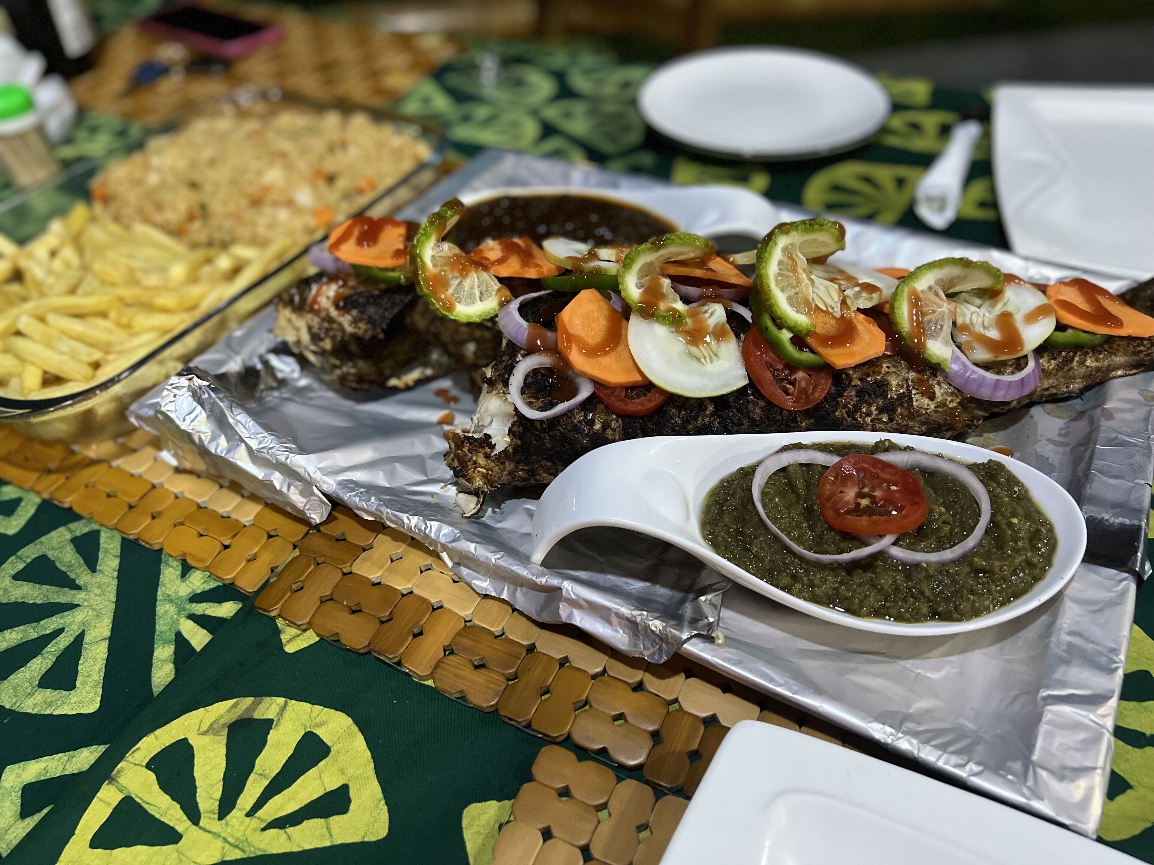 A meal with grilled meat, vegetables, and a side of sauce on a table.