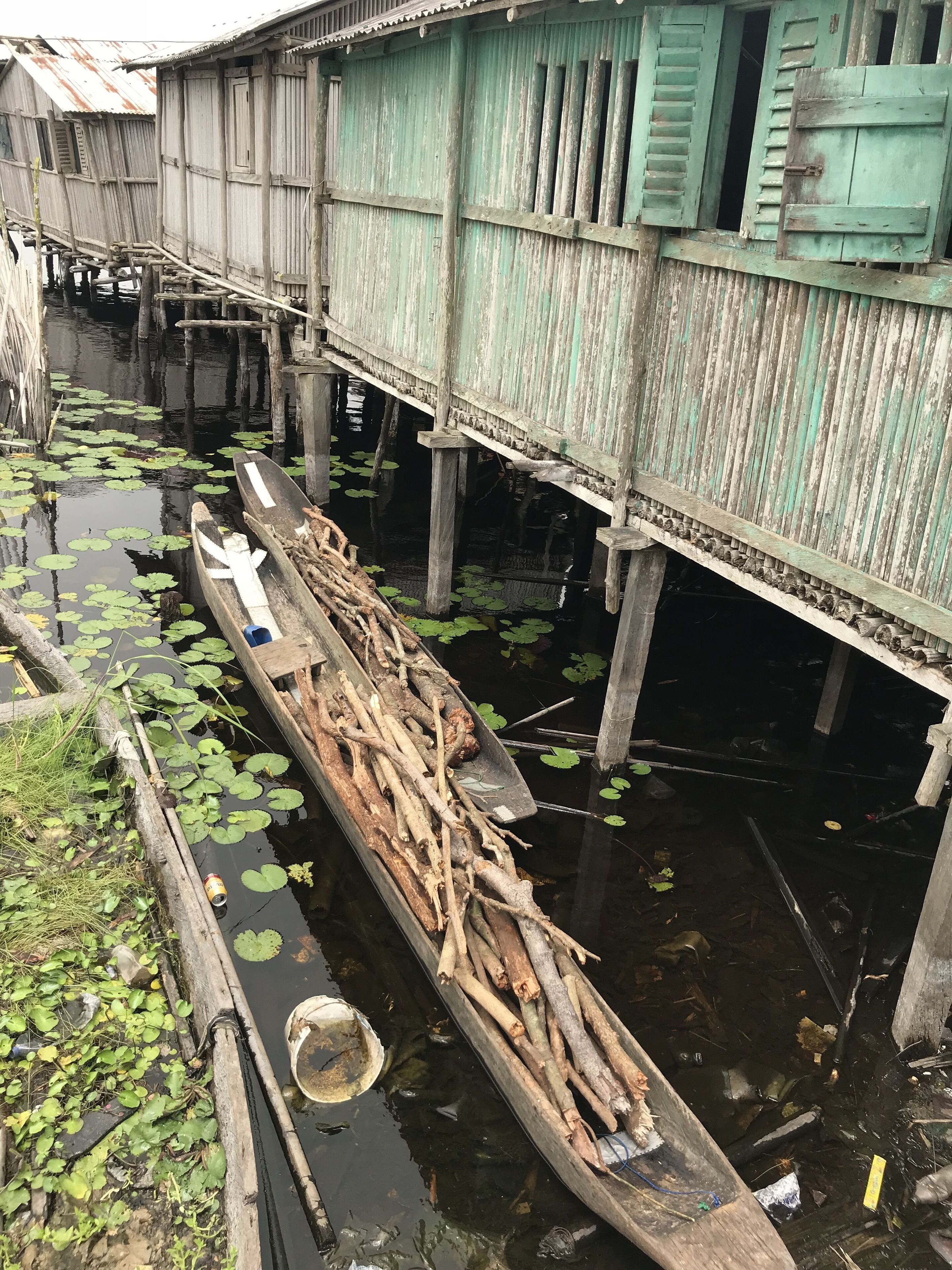 Un bateau en bois, chargé de rondins, était amarré à une structure flottante dont l’extérieur était peint en vert.