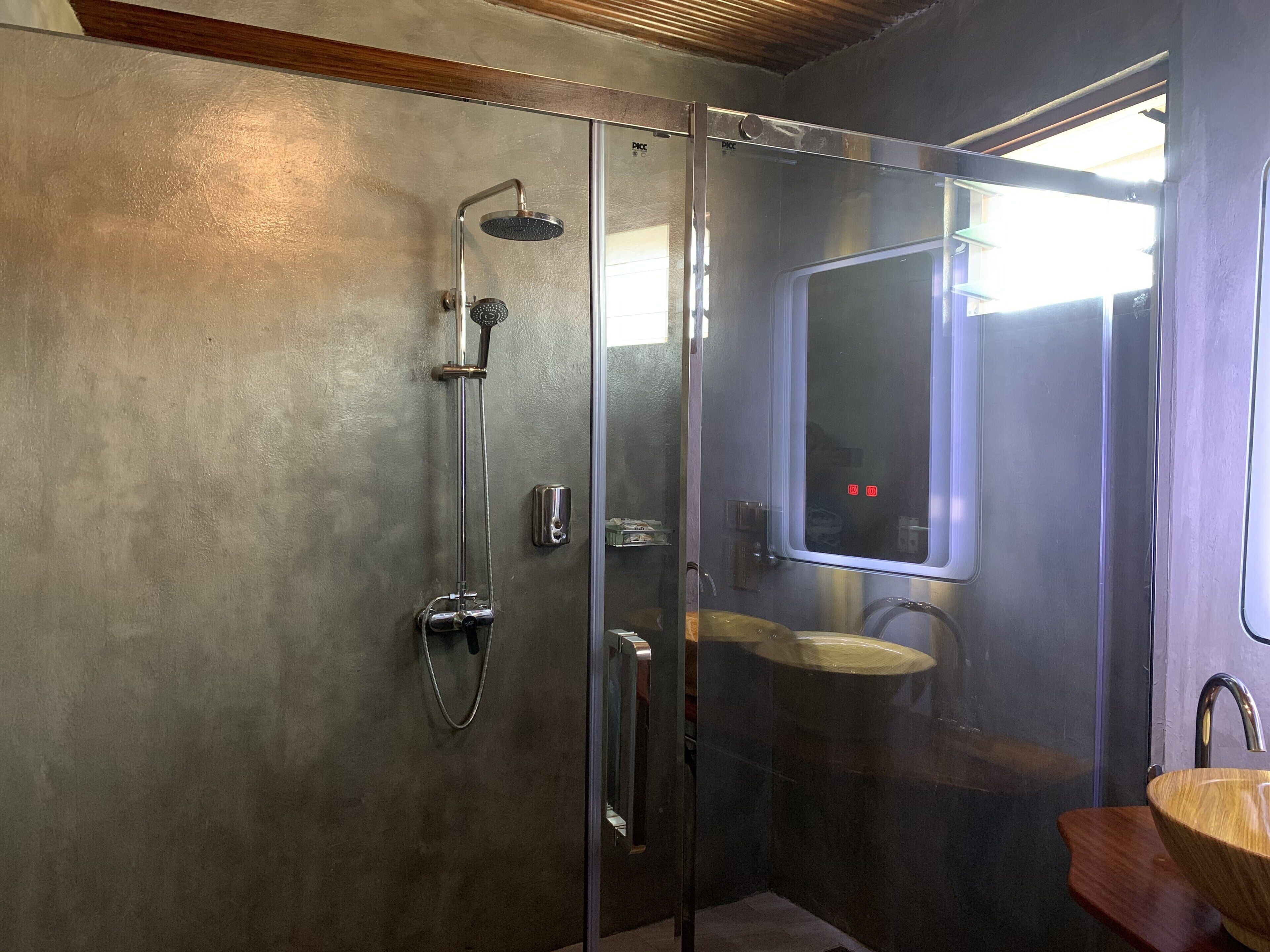 Un baño moderno con ducha acristalada, tocador de madera y un espejo grande.