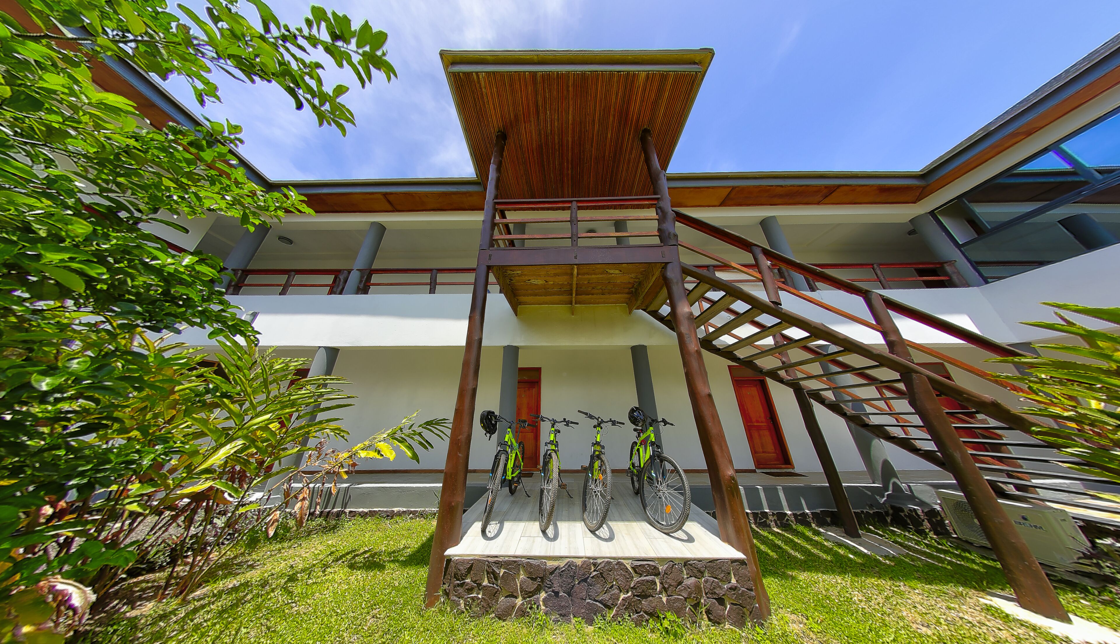 Un edificio de varios pisos con una escalera central, un espacio exterior cubierto y bicicletas estacionadas al frente.
