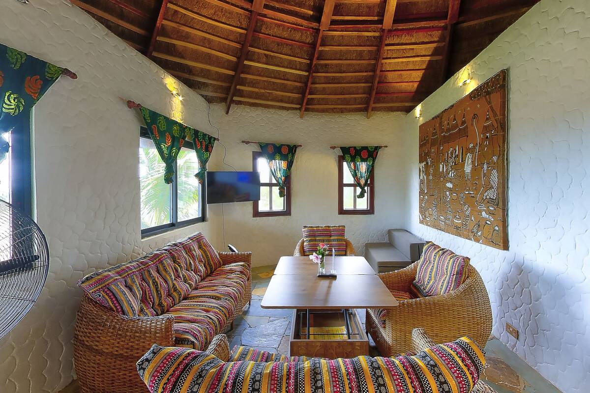 A traditional room with a woven sofa set, a wooden table, and a television mounted on the wall.