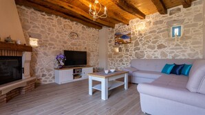 A cozy living room with stone walls, a fireplace, a television, and a sofa. - Beautiful Villa Bogovski Dvori**** with a rustic touch on Krk (Malinska)