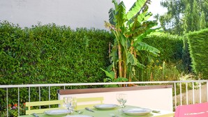 A dining table set outdoors with a white chair and a pink chair.