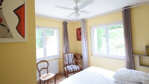 A bedroom with a bed, a chair, a radiator, and a ceiling fan.