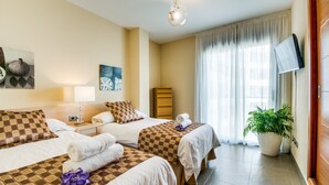 A hotel room with two beds, a TV, a plant, and artwork on the walls. - Apartment Alcudia Portobello with seaview (Puerto de Alcudia)