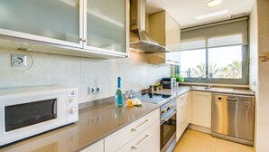 A modern kitchen with a microwave, toaster, and dishwasher. - Apartment Alcudia Portobello with seaview (Puerto de Alcudia)