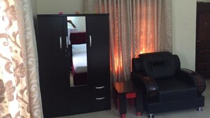 A room with a black wardrobe, a black leather sofa, and a small table. - Valton Hotels Abuja (Abuja)