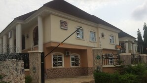 A two-story building with a stone facade, a gated entrance, and a paved driveway. - Valton Hotels Abuja (Abuja)