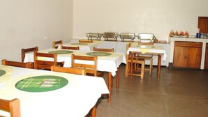 A dining area with multiple tables, chairs, and a kitchen area in the background. - Kolping Hotel Masindi (Masindi)