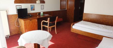 Habitación de hotel con cama, escritorio, silla y una mesita.