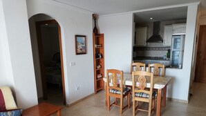 Ein Essbereich mit Holztisch und -stühlen, einer Couch und einer Küche im Hintergrund.