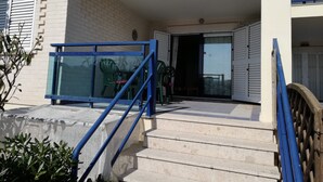 Ein Gebäude mit weißer Fassade, einer blauen Treppe und einer Glastür, die auf einen Balkon führt.