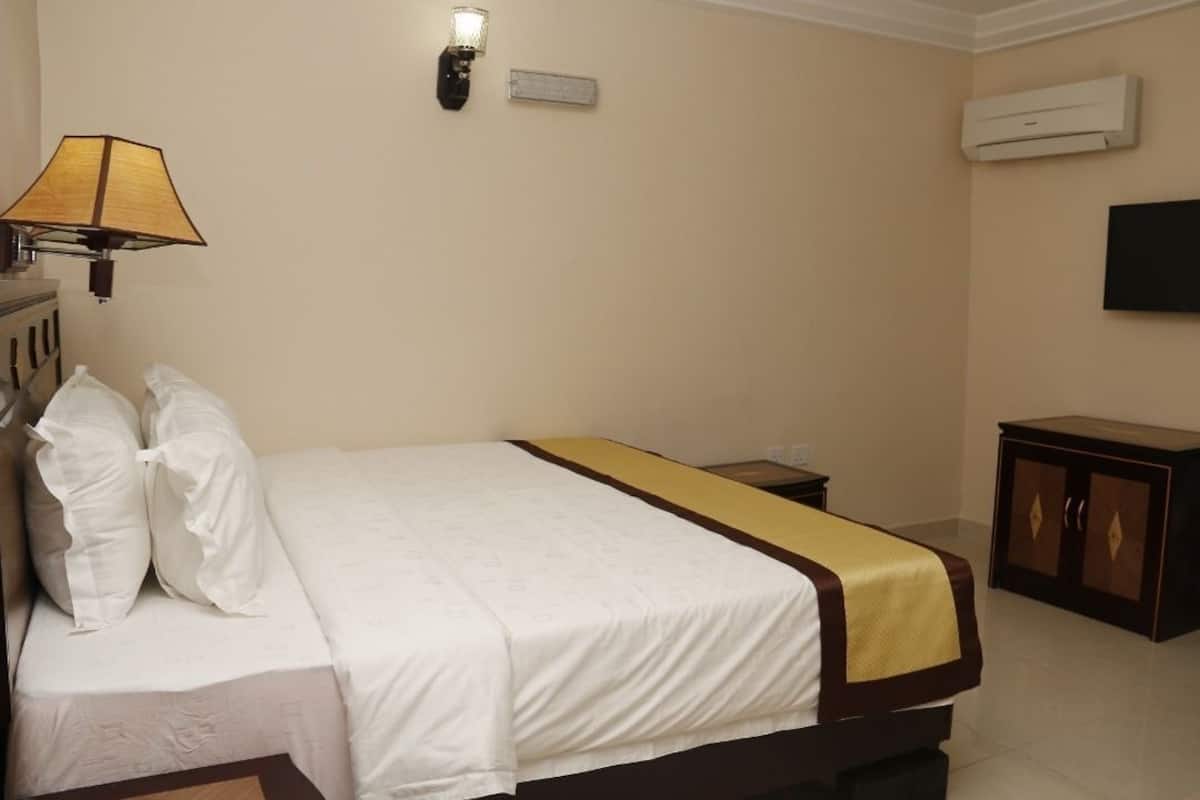 Una habitación de hotel con una cama, una lámpara, aire acondicionado y televisión.