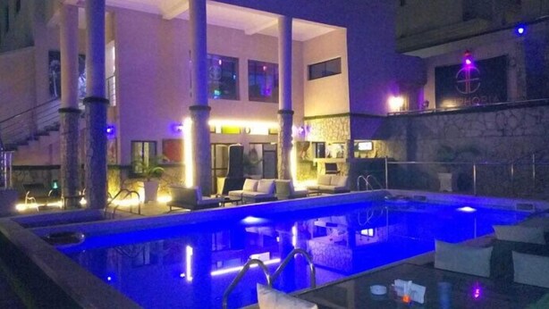 A pool area with lounge chairs and a stone wall. - Commodore Hotel Abuja (Abuja)