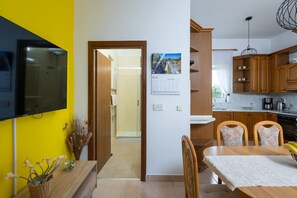 A modern kitchen with wooden cabinets, a built-in oven, and a dining area with a table and chairs.