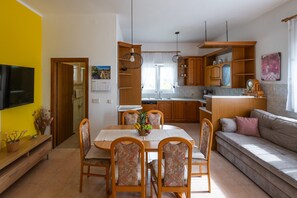 Eine moderne Küche mit Holzausstattung, einem Esstisch mit Stühlen und einer Wohnbereich mit einer Couch.