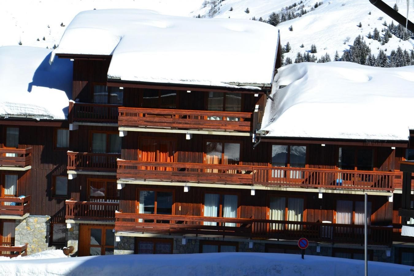 Un bâtiment en bois à plusieurs étages, doté de balcons, entouré d’un paysage enneigé et d’arbres.