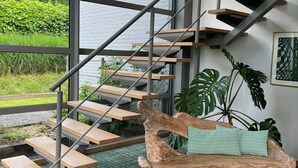Un intérieur moderne avec un escalier, un banc en bois et une grande plante.