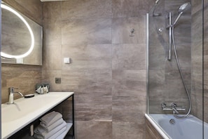 Une salle de bain moderne comprenant un meuble-lavabo, un miroir, une douche avec un pommeau de douche amovible et une baignoire.