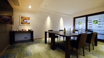 A conference room with a large table, chairs, a small console table with items, and a large window with a view.