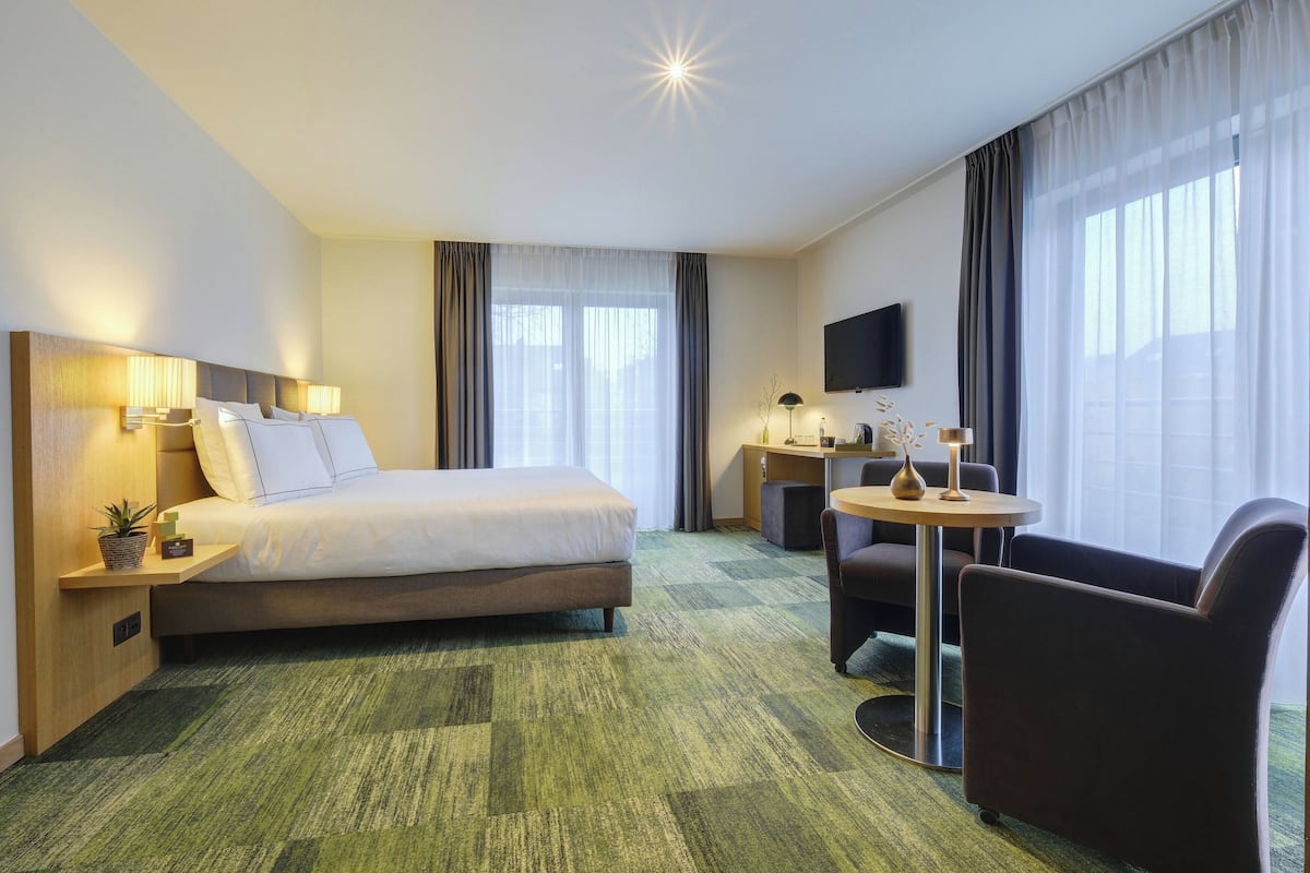 A hotel room with a bed, a desk, a chair, and a TV.