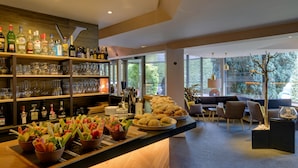 Un espace bar avec des étagères remplies de bouteilles d’alcool, de verres et un buffet proposant divers plats.