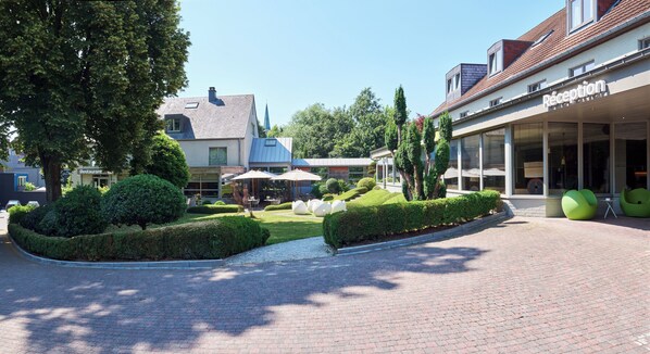 A reception area with a clear pathway, neatly trimmed hedges, and a building with a visible entrance.