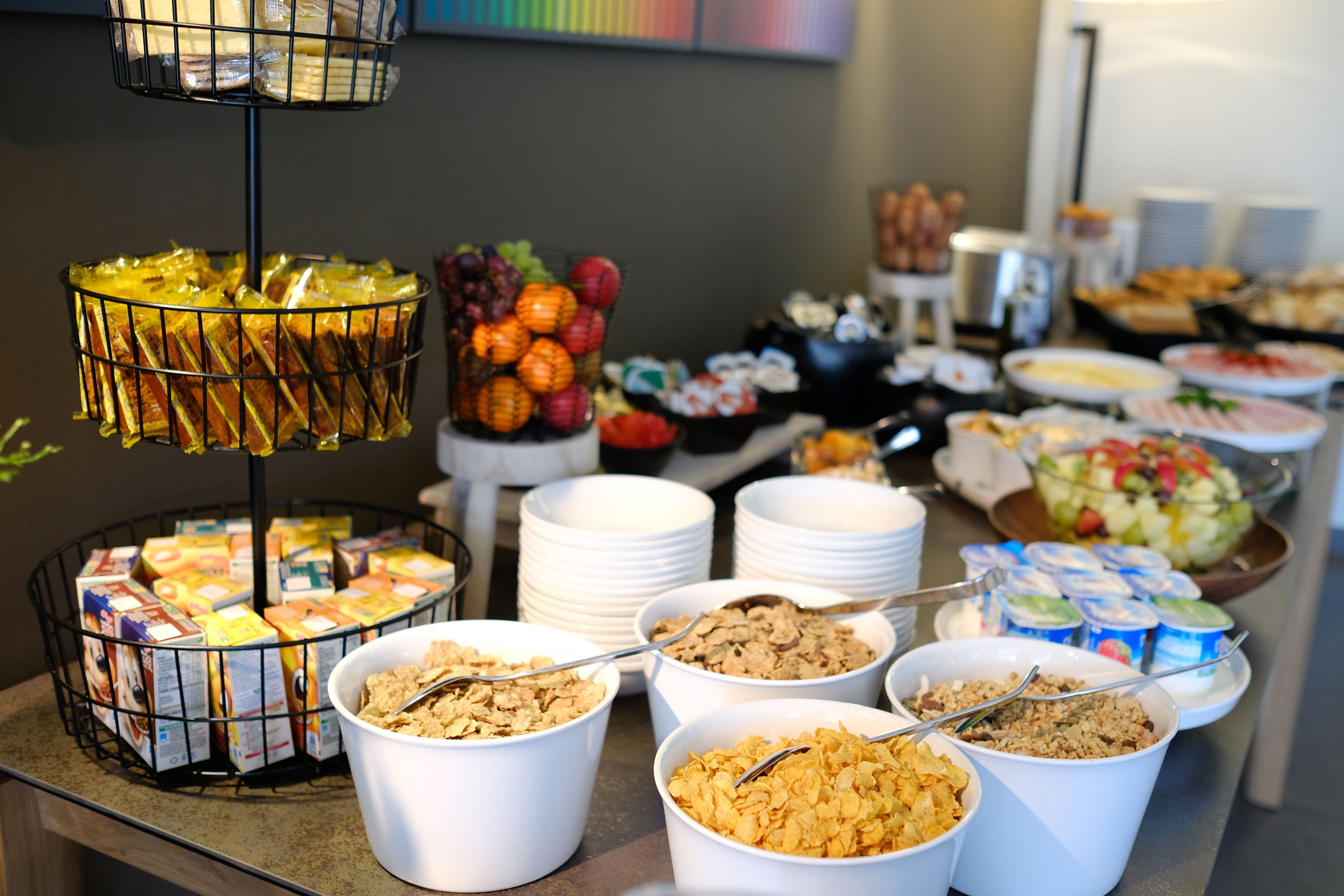 Un bufé con diversas opciones de comida, como cereales, frutas y sándwiches.