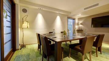 A conference room with a long table, six chairs, and a carpeted floor.