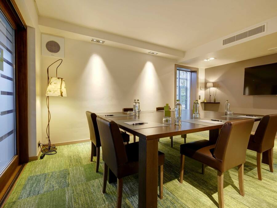 A conference room with a long table, six chairs, and a carpeted floor.
