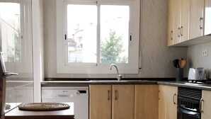Una cocina moderna con lavavajillas, horno y ventana que deja entrar luz natural.