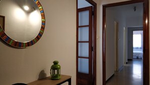 Un pasillo con un espejo, un farol verde y una puerta que da a otra habitación.
