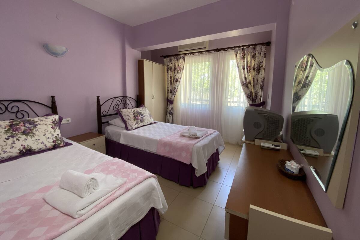 A bedroom with two beds, a wardrobe, a mirror, and a heater.