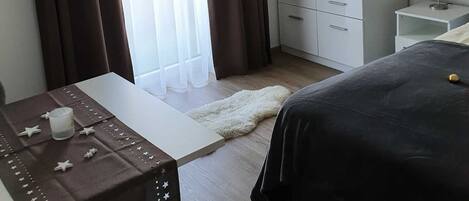A hotel room with a bed, a wardrobe, a bedside table with a lamp, and a small table with a candle and star decorations.