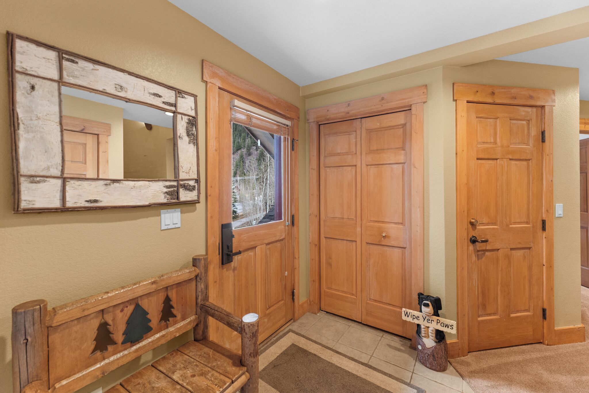 A hallway with wooden doors, a bench, and a mirror on the wall.