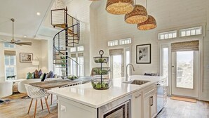 Una cocina amplia con una isla central, una escalera de caracol y ventanas grandes.