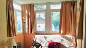 Een slaapkamer met een bed, een stoel, een lamp en een raam met gordijnen.