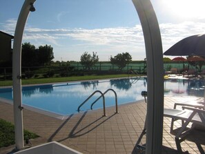 Una piscina al aire libre de temporada, sombrillas, tumbonas