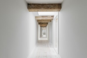 A narrow hallway with white walls and a wooden floor.