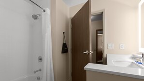 A bathroom with a bathtub, a sink, and a wooden door. - Holiday Inn Express & Suites Fayetteville South by IHG (Fayetteville)