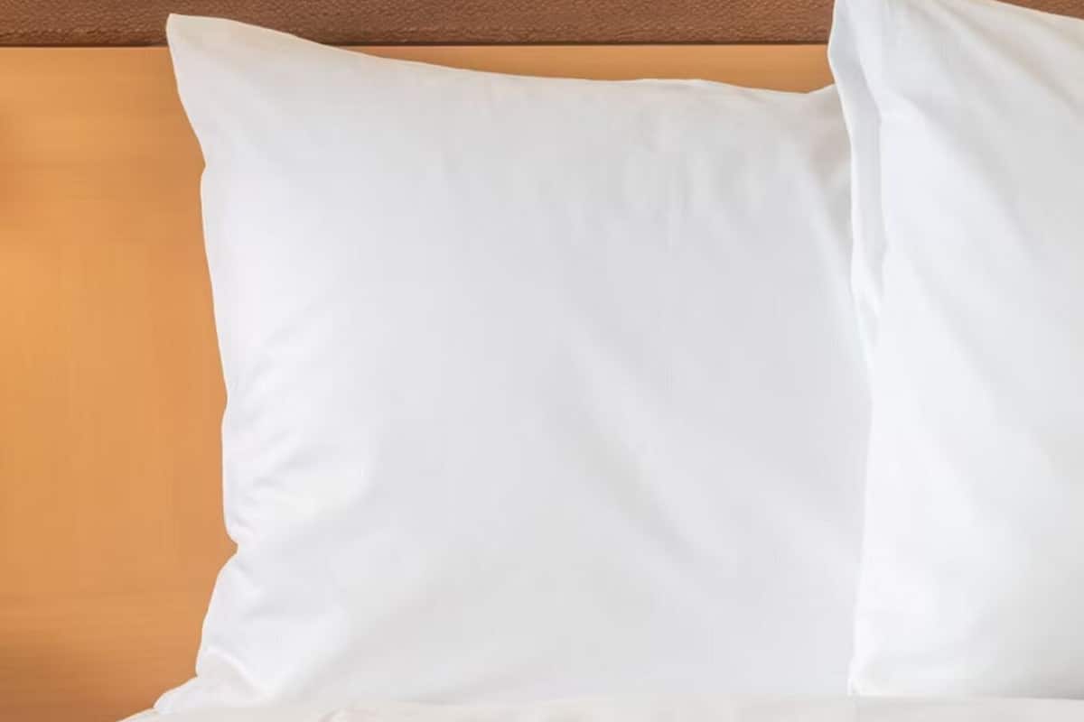 Una cama con almohadas blancas y cabecera de madera.
