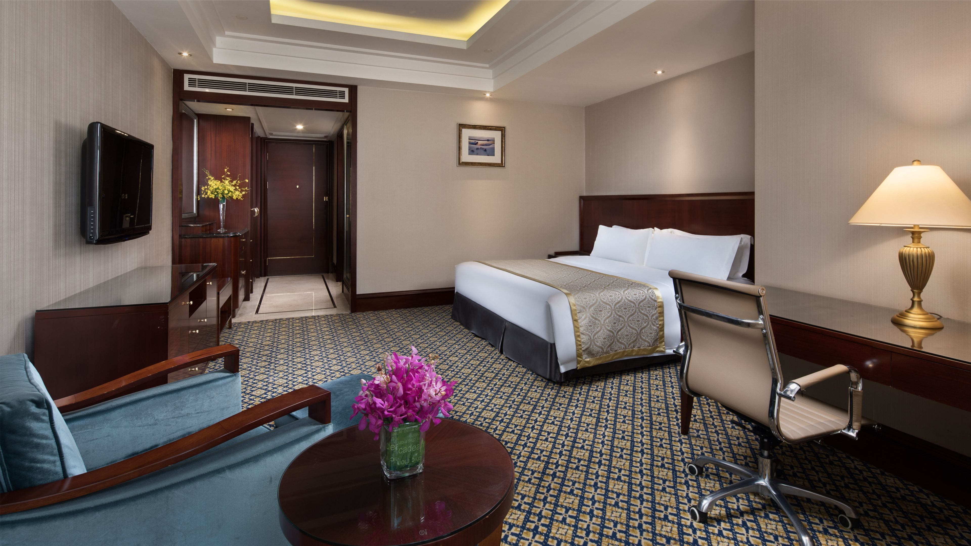 Une chambre d’hôtel avec un lit, un bureau, une chaise, une télévision et une lampe.