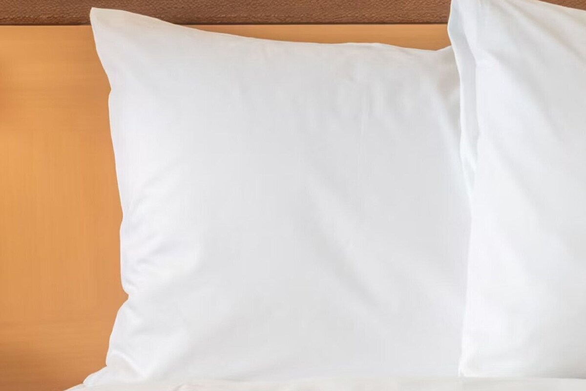 A bed with white pillows and a wooden headboard.
