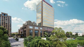 Un hôtel moderne doté d’une façade en verre remarquable, d’une terrasse sur le toit et d’un jardin bien entretenu.
