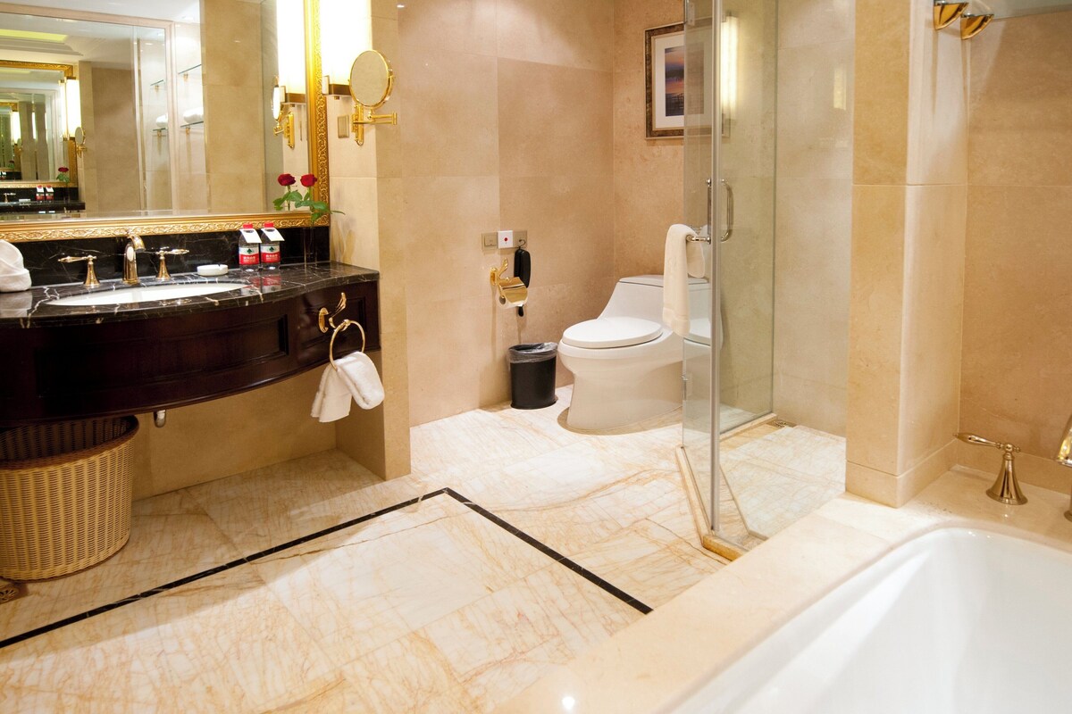 A bathroom with a marble floor, a bathtub, a toilet, and a sink with a vanity.