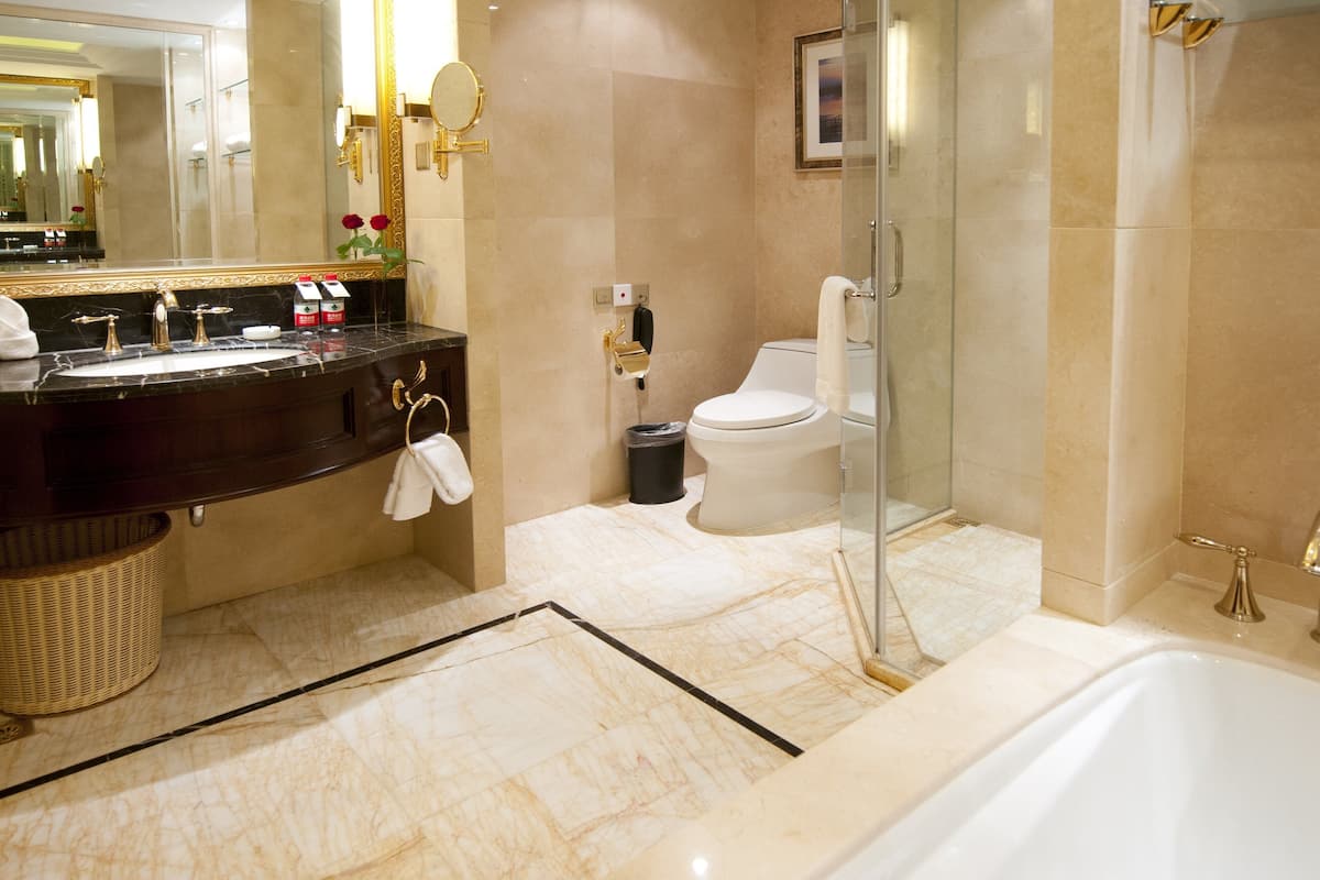 Un baño moderno con piso de mármol, bañera, inodoro y zona de ducha.