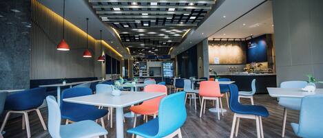A modern restaurant interior with a variety of seating options, including tables and chairs, and a bar area in the background.