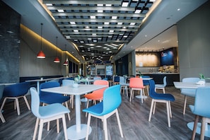 A modern restaurant interior with a variety of seating options, including tables and chairs, and a bar area in the background. - Holiday Inn Express Ningbo Fenghua by IHG (Ningbo)