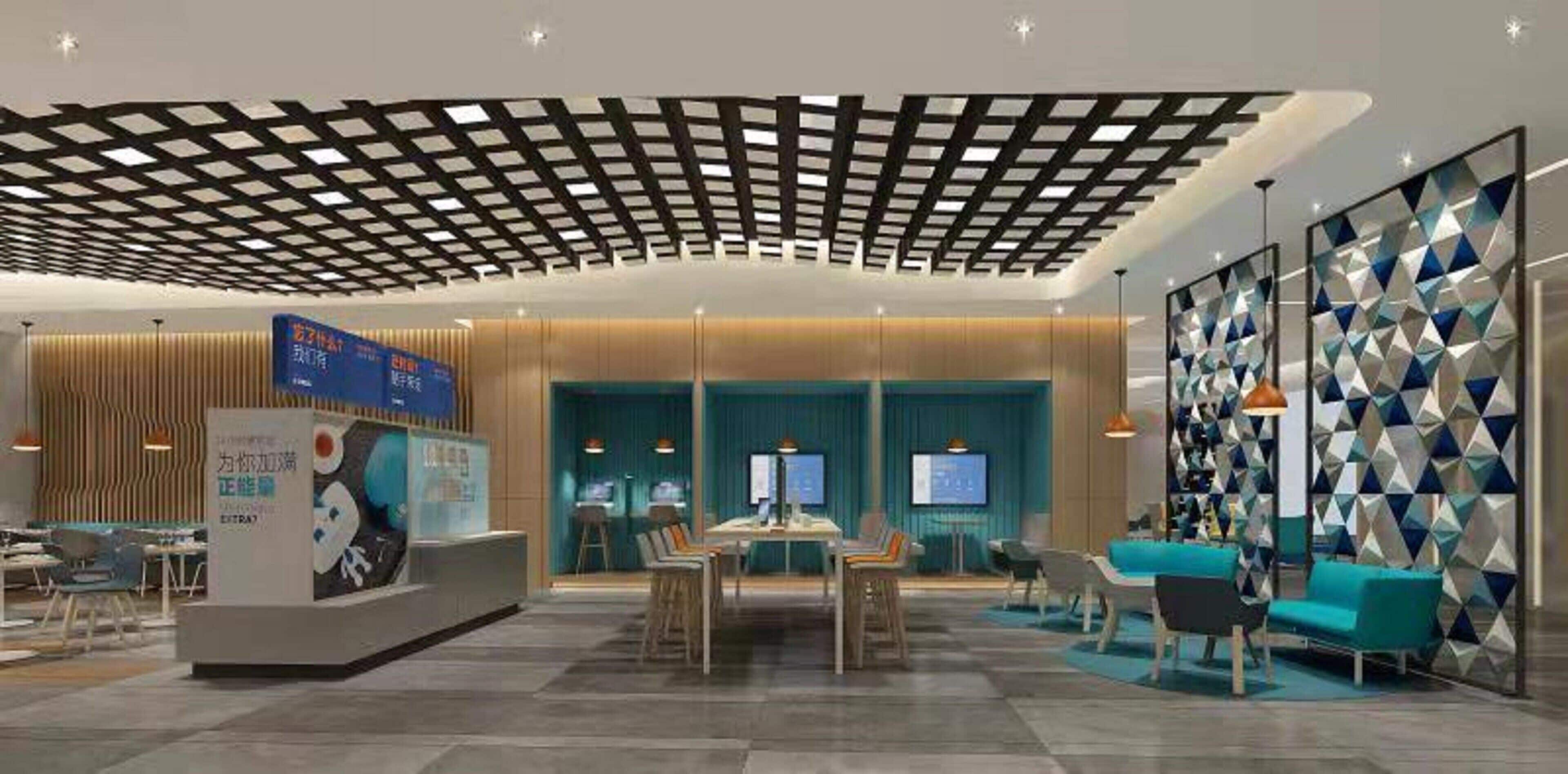 A modern lobby with a checkered ceiling, a reception desk, seating area, and a wall with geometric patterns.
