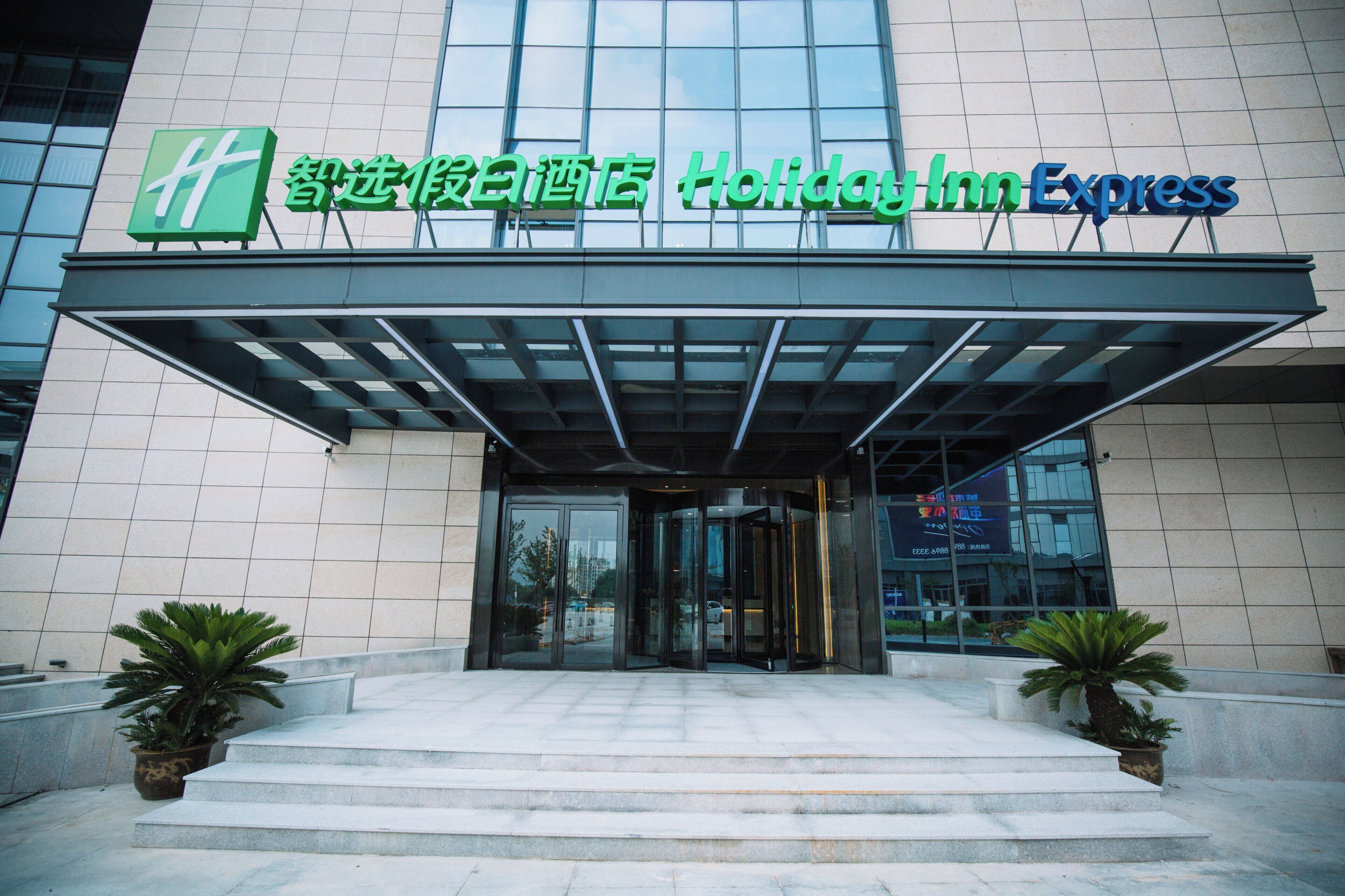 L’entrée d’un hôtel Holiday Inn Express, avec une façade en verre et un espace d’entrée abrité.